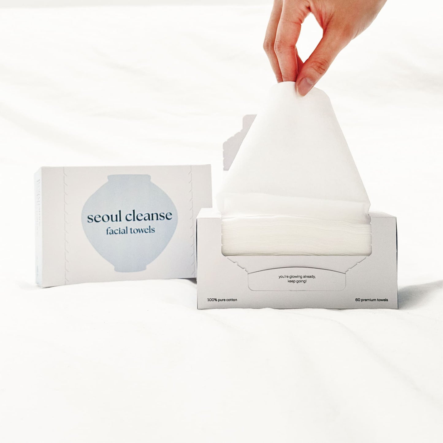 Seoul Cleanse facial towels with a hand pulling out a towel from the box on a white background